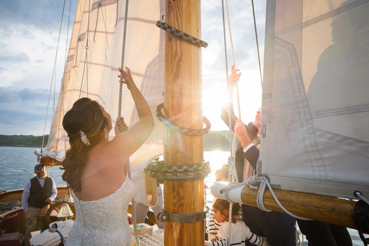 Newlyweds hoisting the mainsail aboard the Schooner Olad in Camden, Maine © 5iveLeaf Photography